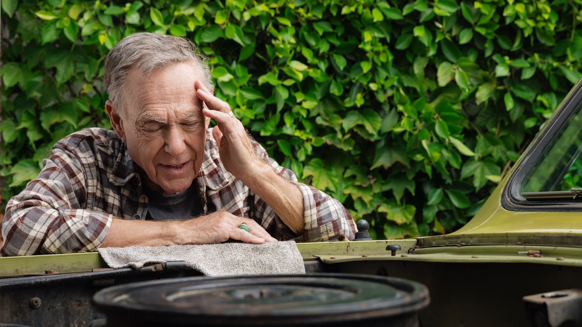 Man in pain as he works on his car.