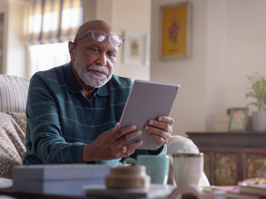 Elderly man researching heart valve disease on his tablet.